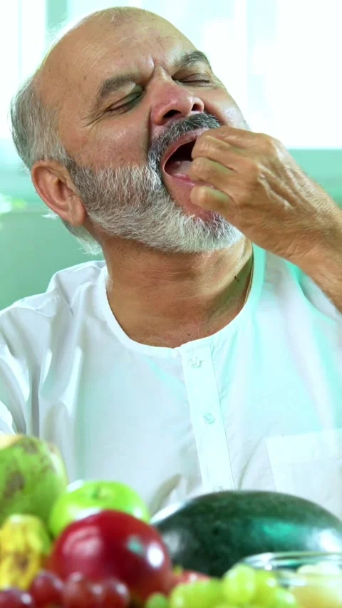 Senior Indian man sitting with snacks, reacting joyfully to tasty Video stock 343106871