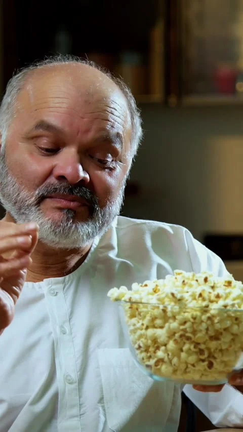 Senior Indian man sitting with snacks, reacting joyfully to tasty Stock Footage 343107032