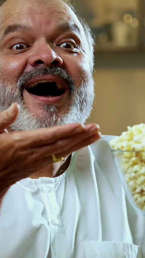 Senior Indian man sitting with snacks, reacting joyfully to tasty Stock Footage 343107034