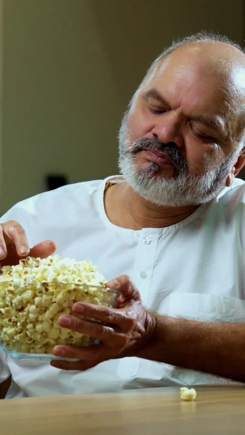 Senior Indian man sitting with snacks, reacting joyfully to tasty Stock-Footage 343107039
