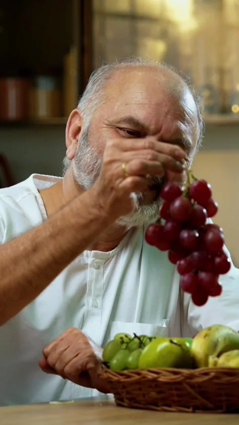 Senior Indian man sitting with snacks, reacting joyfully to tasty Stock Footage 343107096