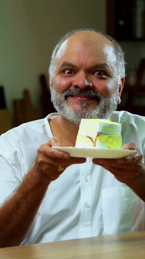 Senior Indian man sitting with snacks, reacting joyfully to tasty Stock-Footage 343107161