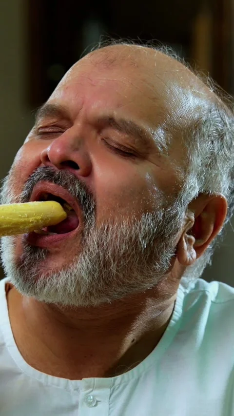 Senior Indian man sitting with snacks, reacting joyfully to tasty Video stock 343107174