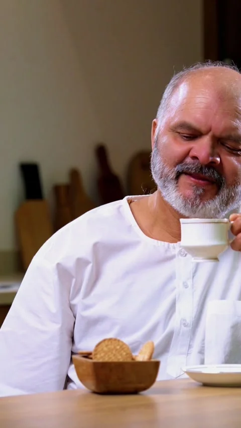 Senior Indian man sitting with snacks, reacting joyfully to tasty Stock Footage 343107225
