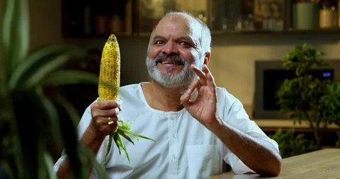 Senior Indian man sitting with snacks, reacting joyfully to tasty Stock-Footage 343139470