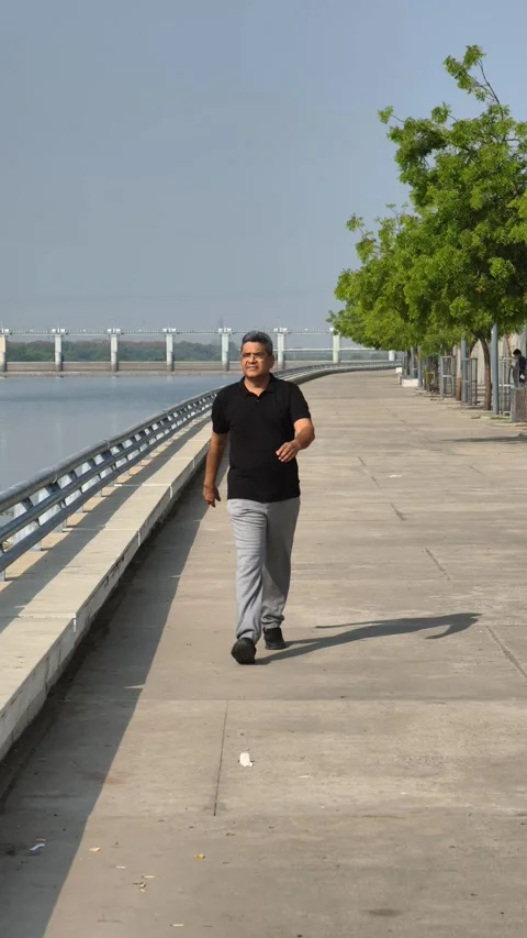 Senior Indian man walking confidently at Riverfront Ahmedabad in the morning Stock Footage 309650211