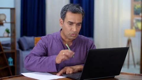 A senior Indian professional making notes with a laptop screen in front - off... Stock Footage 204838136