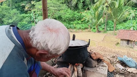 Senior Indonesian farmer cooking water outdoors. Stock Footage 321931053