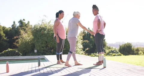 Senior instructor stepping forward, cuing hip alignment and guiding women banded Stock Footage 334925303