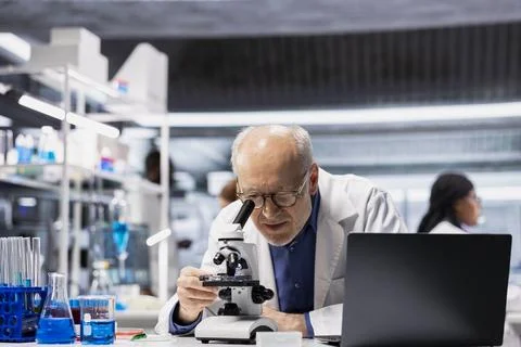 Senior lab manager examining stained tissue under microscope Stock Photos