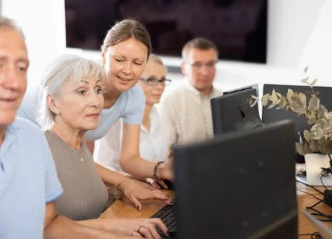 Senior lady attending computer class under guidance of young female teacher Fotos de archivo
