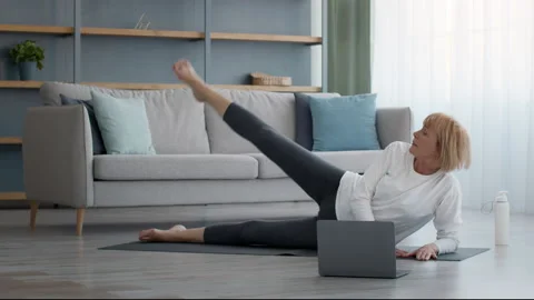 Senior Lady Doing Leg Raise Exercise At Laptop At Home Stock Footage 158152822