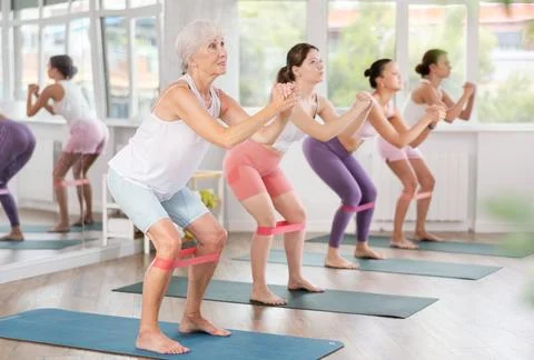 Senior lady exercising with resistance loop band during pilates class Photos