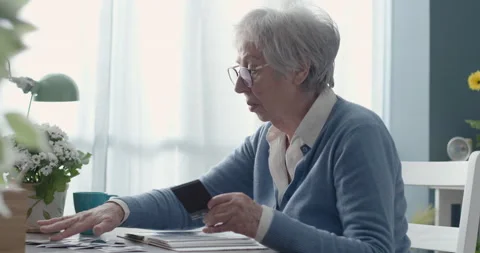 Senior lady looking at her old pictures Stock Footage 151197163