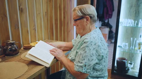 Senior lady looks through nostalgic photo collection. Elderly grandmother fondly Stock Footage 345150938