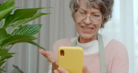 Senior lady makes a video call by her phone, family relations on disance, 4k Stock Footage 240010242