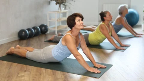 Senior lady performs cobra pose, Bhujangasana Stock Footage 303882551