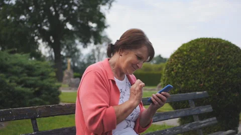 Senior lady using smartphone on a bench in park Stock Footage 151749158