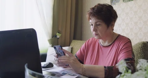 Senior lady using smartphone watching video sit couch, middle aged woman grandma Stock Footage 129379205