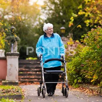 Senior lady with a walker in autumn park Stock Photos