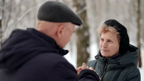 Senior living couple are resting in forest in winter, old man is holding hands Stock Footage
