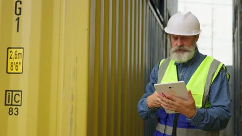 Senior logistics manager communicates on a radio and uses a tablet Stock Footage 342280412