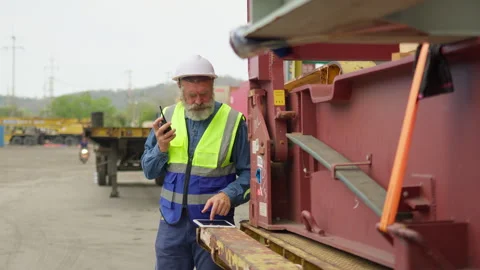 Senior logistics manager coordinates freight shipment using a tablet and radio Stock Footage 342280124