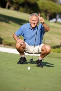 Senior Male Golfer On Golf Course Lining Up Putt On Green Stock Photos