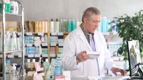 Senior male pharmacist uses computer at workplace. Stock Footage 332735785