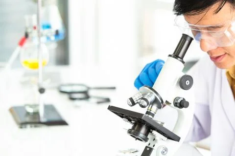 Senior Male scientist looking through a microscope in Central laboratory. Stock Photos