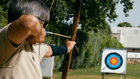 Senior man aiming bow at archery target Stock Photos