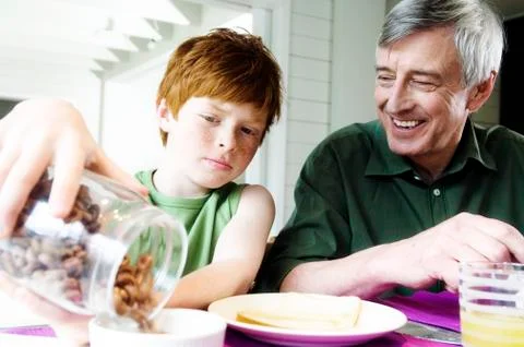 Senior man and boy having breakfast Stock Photos