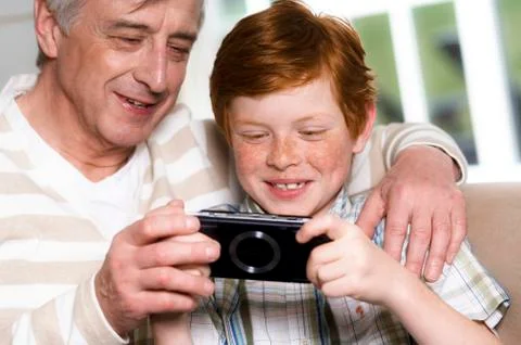 Senior man and boy playing Playstation Portable Stock Photos