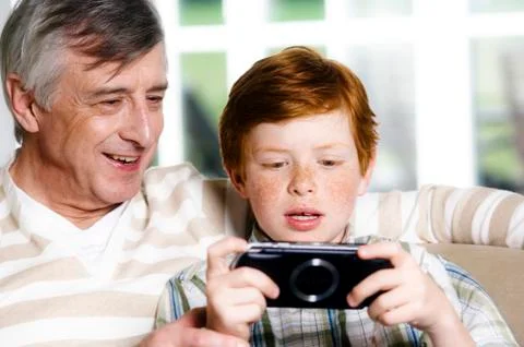 Senior man and boy playing Playstation Portable Stock Photos
