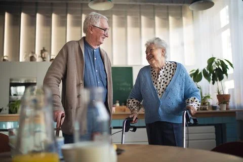 Senior man and woman walking with walker indoors in retirement nursing hme. Stock Photos