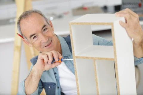 Senior man assembling flat pack furniture Stock Photos