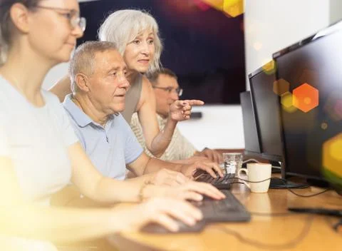 Senior man attending computer class under guidance of aged female teacher Fotos de archivo