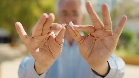 Senior man breaking cigarette at park Stock Footage 199770067