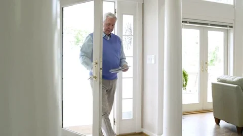 Senior man bringing mail into a dining room Stock-Footage 83394629