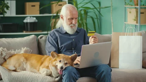 Senior Man Browsing Internet, Shopping Online Sitting on Sofa with Corgi Stock Footage 196255234