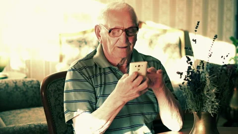 Senior man browsing smarthone by table, at home, 4K 스톡 동영상 105294531