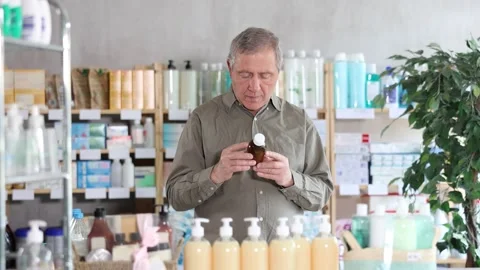 Senior man buys expectorant syrup at pharmacy Stock Footage 317986945