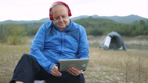 Senior man camping with tent using tablet with mountain lake on background - Stock Footage 168251290