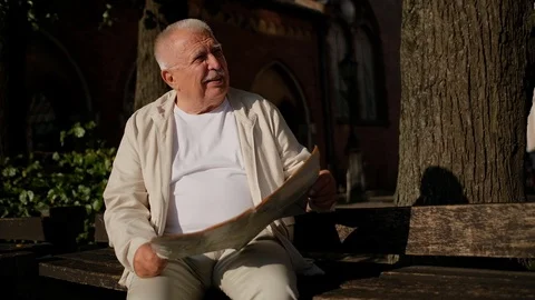 Senior man in casual clothes with map looks around in park Stock Footage 115884401