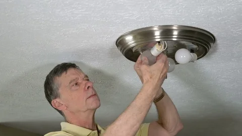 Senior man changing LED bulb in light fixture Stock Footage 74504286