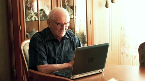 Senior man chatting on laptop by table at home Stock Footage 100158430