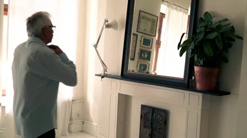 Senior man checking his appearance and using perfume in front of the mirror Stock Footage 106199595