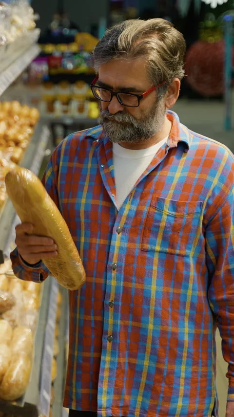 Senior man choosing bread at grocery store bakery aisle Stock Footage 309066032