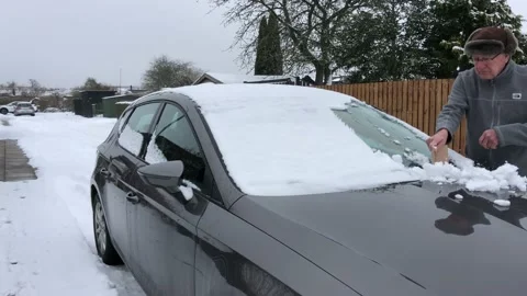 Senior man cleaning windscreen from snow Stock Footage 148543529