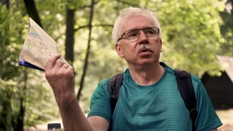 Senior man cooling himself with map sitting on bench park Stock Footage 88428140